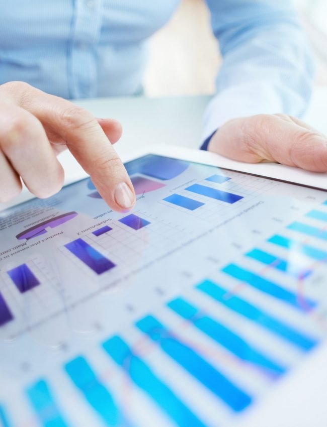 Image of human hand pointing at touchscreen with business document